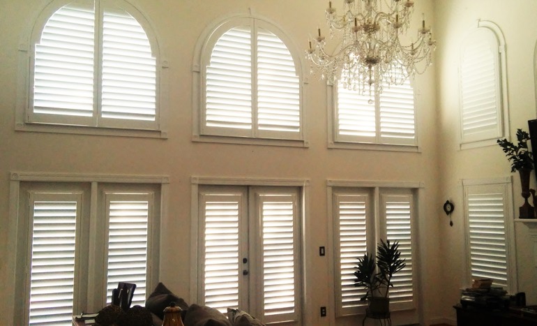 Entertainment room in two-story New Brunswick home with plantation shutters on arch windows.