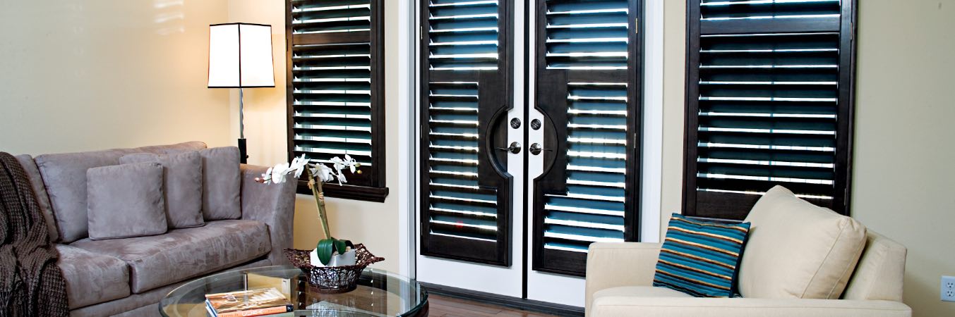 Wood plantation shutters customized for French patio doors and surrounding windows.
