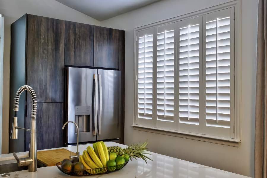 Homeowners use indoor window shutters in New Brunswick when they want attractive and functional window treatments. Polywood shutters on a large kitchen window