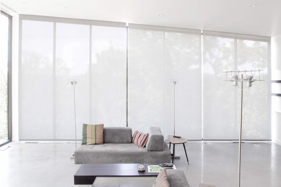 Motorized window shades make controlling natural light effortless in your New Brunswick great room. White motorized shades on a wall of tall great room windows