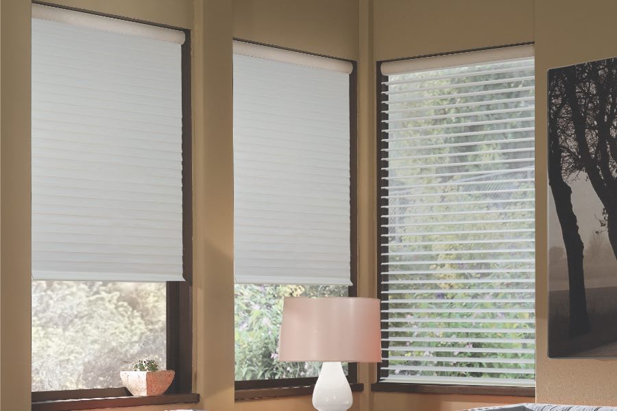 Opaque motorized window shades in New Brunswick keep hot UV rays out of your home. Gray motorized sheer shades on corner windows next to gray furniture