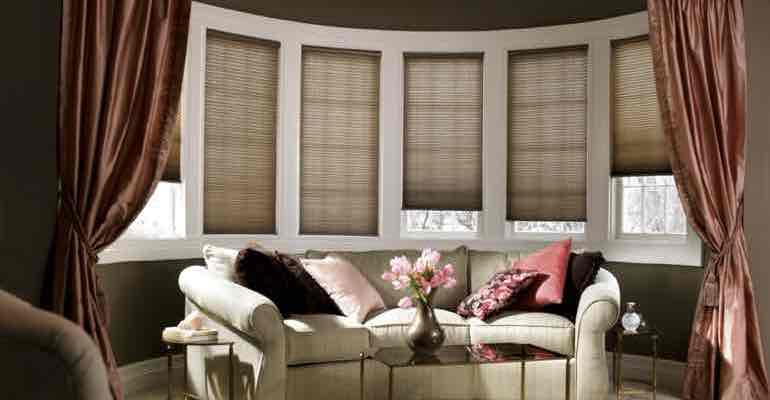 Brown cellular shades in living room bow window.