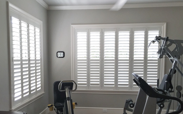 Weatherstripping window coverings are especially important in rooms with windows on more than one wall. New Brunswick home gym with shuttered windows.