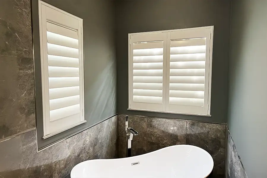 White Polywood shutters above a tub in a bathroom