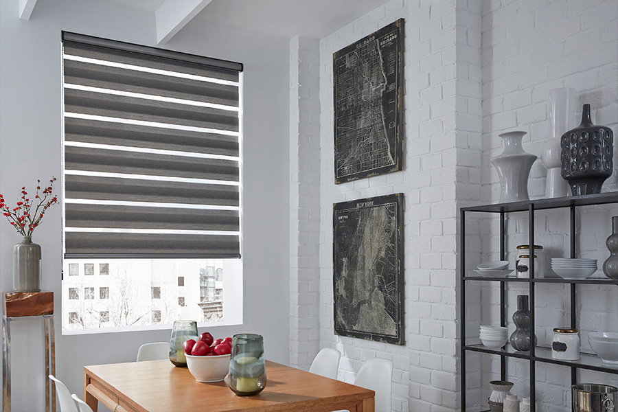 Transitional shades have stripes of material that help a small window look wider and give you flexibility in controlling natural light. Horizontal striped gray shades on a tall window within a breakfast nook area.