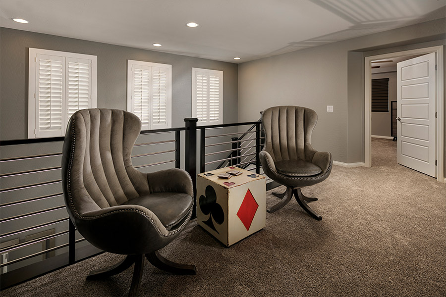 A white window treatment on a darker wall can do wonders for your New Jersey home. two chairs and a small dice-themed table in front of a stairwell with shuttered covered small windows