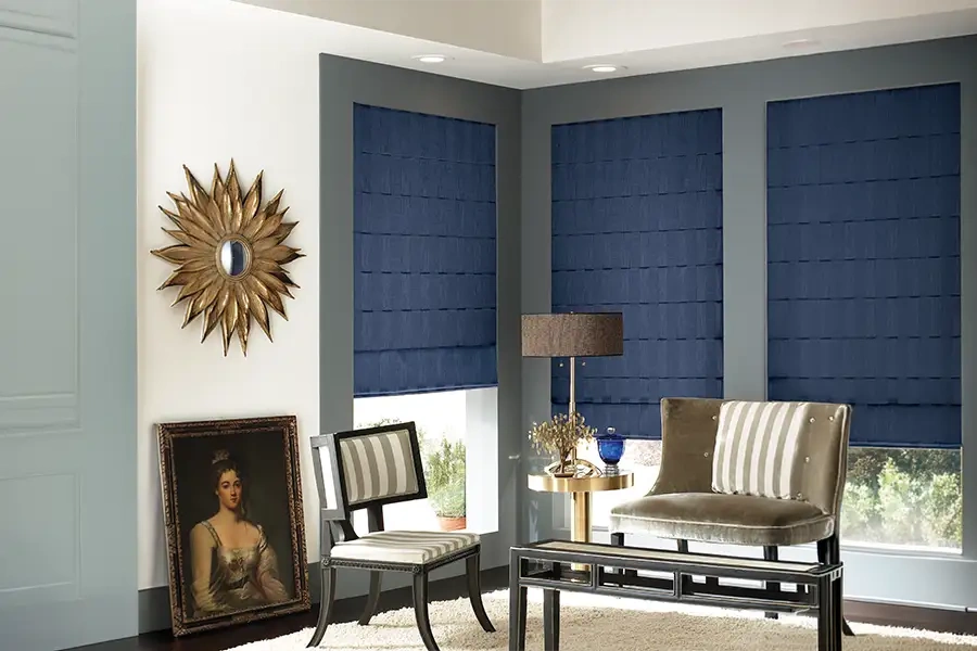 Inside-mount window treatments like these blue Roman shades work well in tight corners where space is limited. Blue Roman shades in a corner of a formal living area
