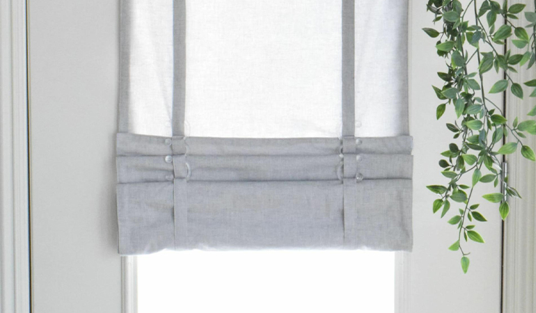 With a tiered tumble shade in New Brunswick, you can block sun glare all year round. Gray rolled tumble shade on a glass door